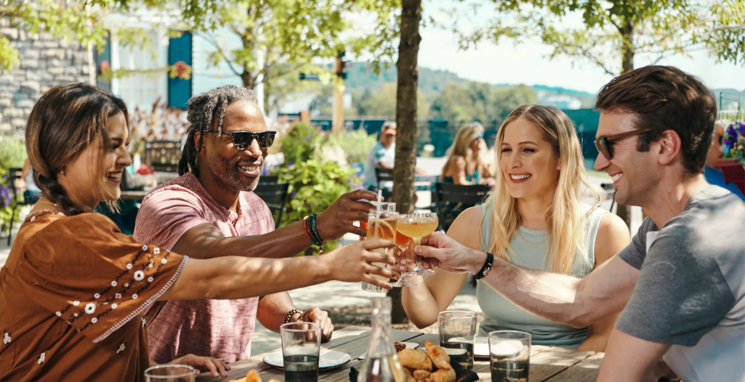 A group of friends sitting outside holding up glasses of Bourbon.